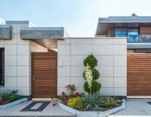 Contemporary house exterior featuring a stylish wooden facade, entrance gate, and vibrant garden.